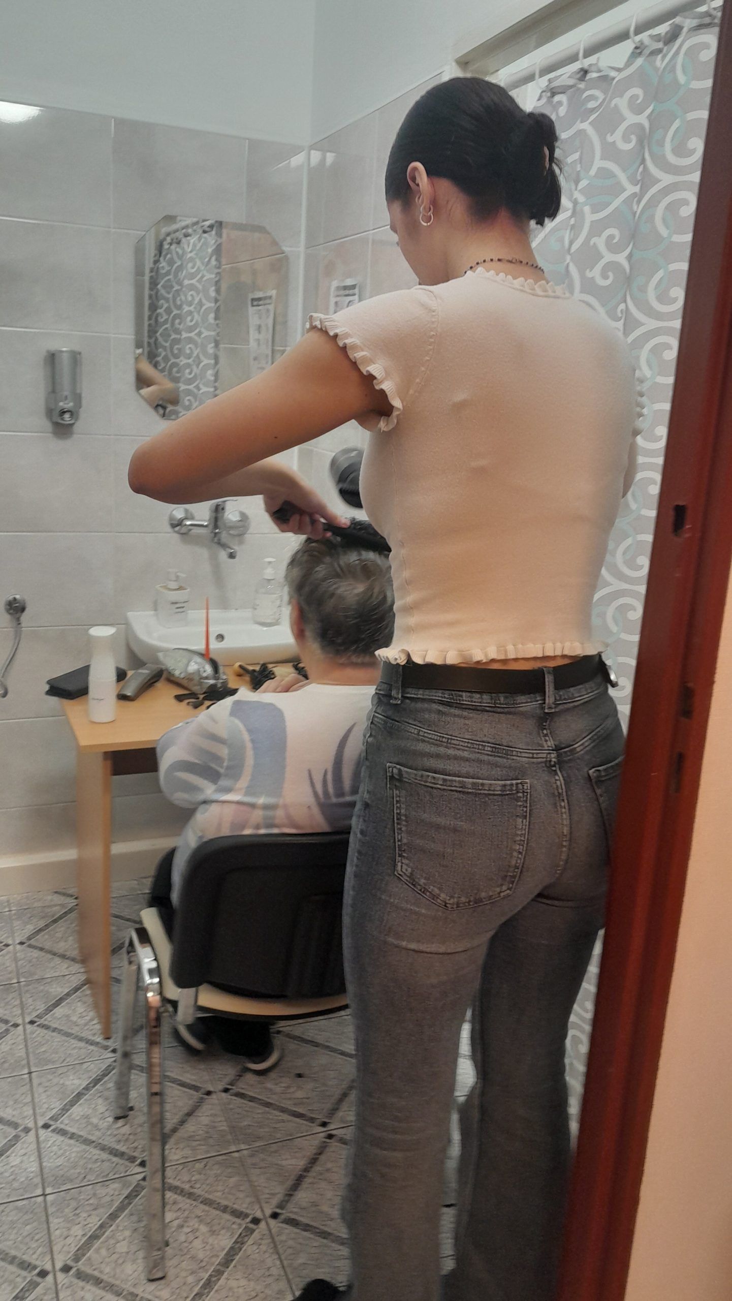 Wykonywanie zabiegów fryzjerskich na głowie starszej osoby